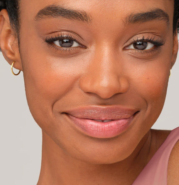 image of woman smiling holding face bronzing powder
